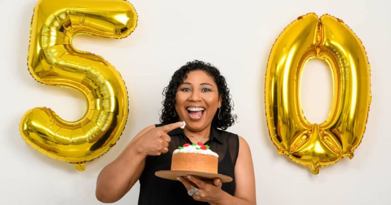 A woman holding a cake celebrates her birthday with a golden 50 balloon.