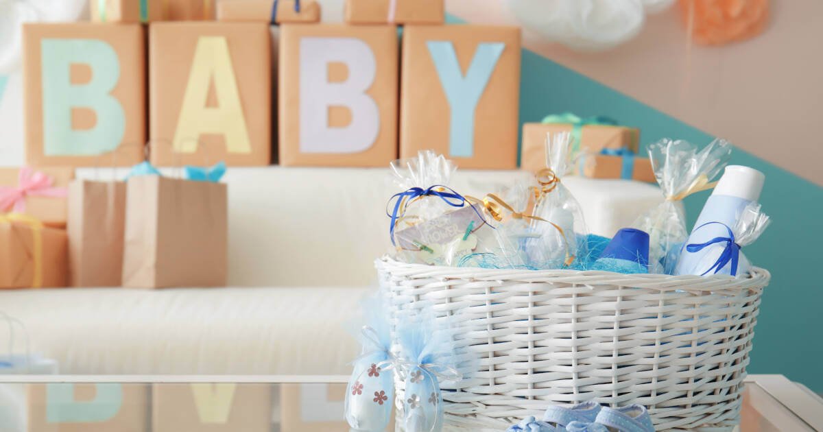 Wicker basket filled with practical gifts for a baby, set on a table indoors.