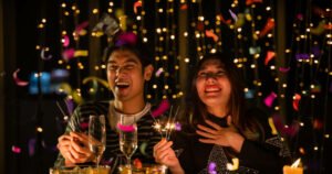 Young couple celebrating at a night party. A candlelit dinner adds to the warmth and coziness of their anniversary.