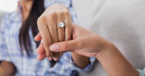 Engagement ring on a woman's hand, held by her friend, symbolizing the joyous moment of commitment.