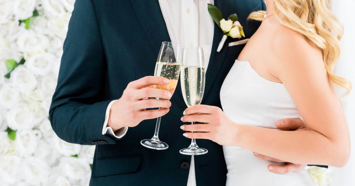 Bride and groom, glasses of champagne in hand, stand together on their wedding day.