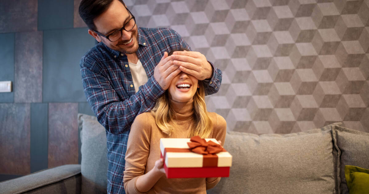 A heartwarming moment as a wife receives a surprise gift box from her thoughtful husband at home.