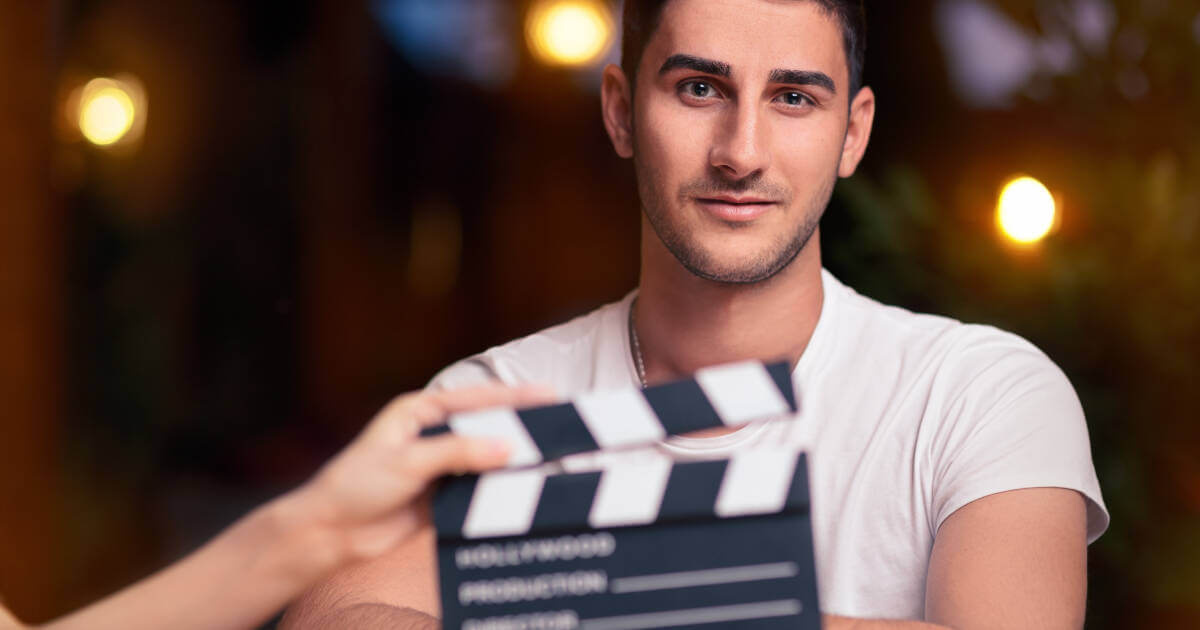 Handsome actor ready for shoot, clapboard in front, poised for a new scene.