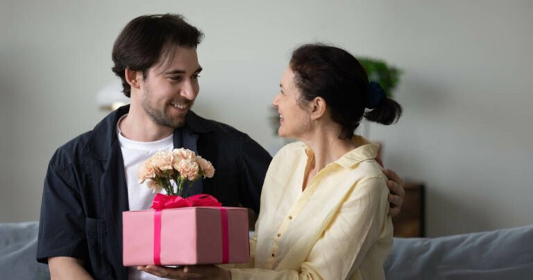 Smiling man presents gifts to girlfriend's mother on sofa.