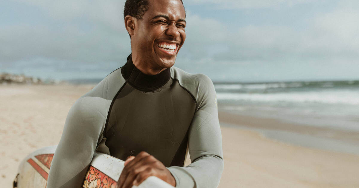 Cheerful man with surfboard, soaking up the beach vibes