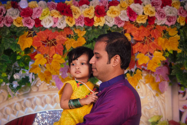 An uncle stands holding his niece as they share a heartfelt moment.