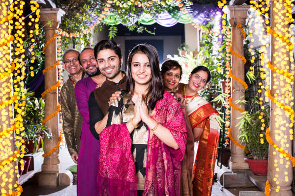 Bride and groom posing with both sets of parents behind them.