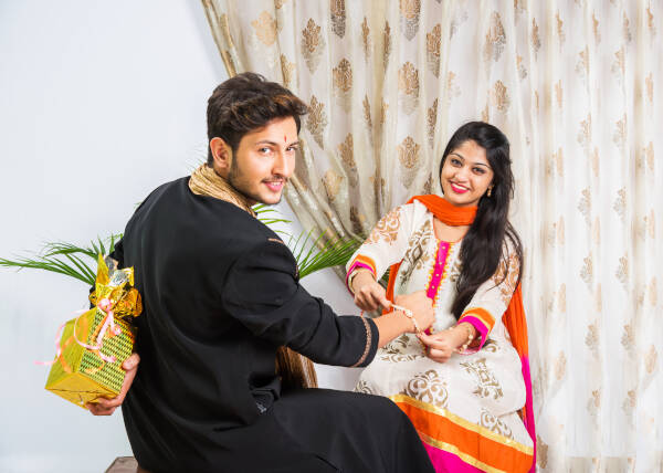 Brother hides a gift behind his back, ready to present to his sister.