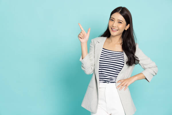Businesswoman points up, smiling, isolated on green background