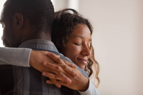 Close-up of young woman embracing her ex-boyfriend, expressing complex emotions