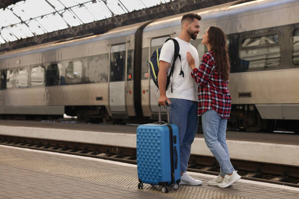 Couple on railway station platform; boyfriend with bags, indicating time apart.