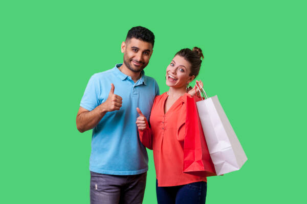 Ex-husband and wife with shopping bags give thumbs up to camera against green background