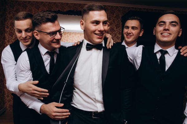 Four friends happily gather around the groom, all smiling in suits