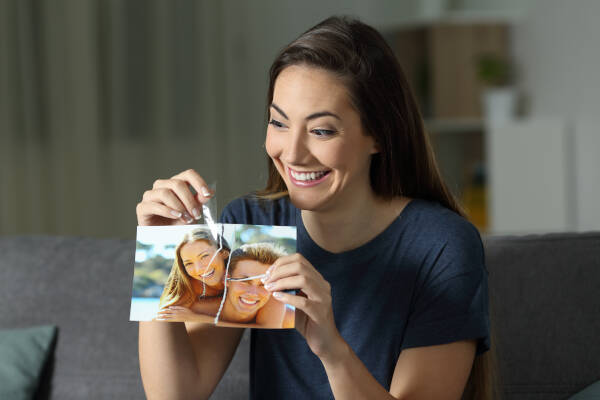 Girl glues couple photo of ex and her after breakup, sitting on couch at home late at night