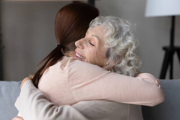 Grateful elderly grandmother, a pensioner, holds her adult daughter in her arms, who is expressing thanks