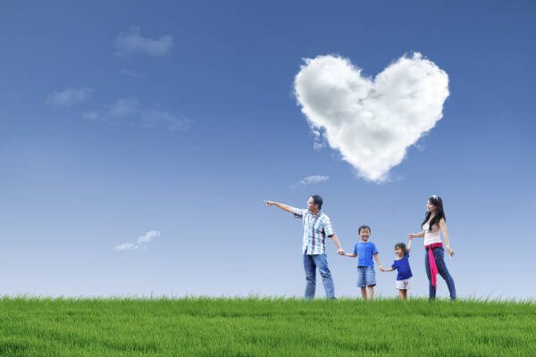 Happy family walking in the park under a sky filled with love