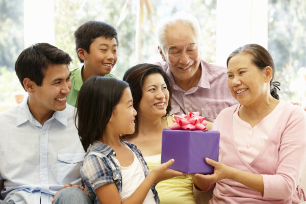 Happy three-generation family celebrates as the oldest woman receives a birthday present