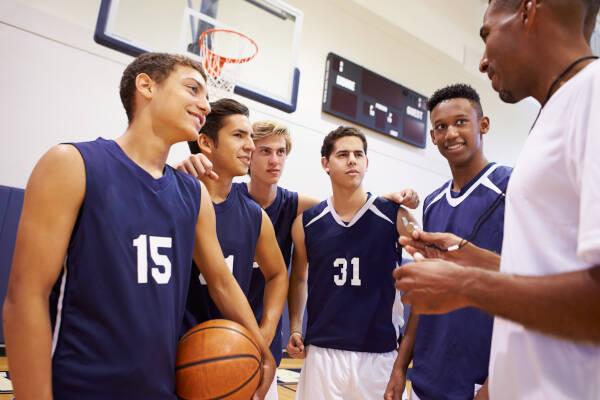 High school basketball team gathers for a team talk with their coach, preparing for the game with focus and determination