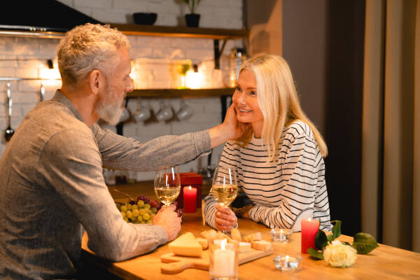 Mature man gently touches his wife's face during a romantic date in the kitchen