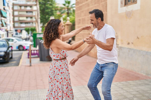Middle-aged couple smiles, dancing confidently in the street