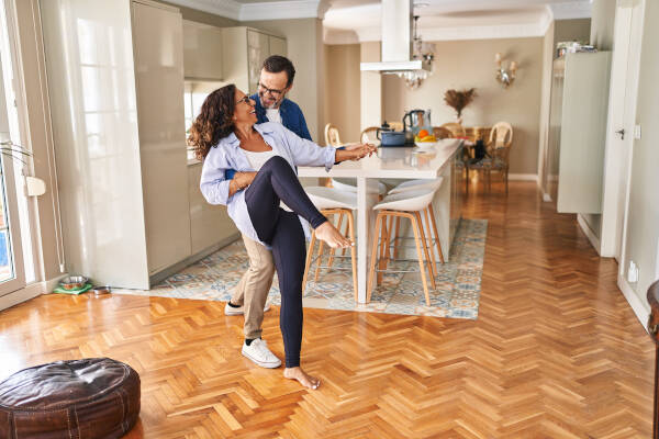 Middle-aged couple smiling as they dance in their house