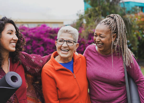 Multi-generational women embrace happily after a yoga session in the city park.