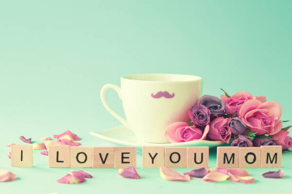 Scrabble pieces spell 'I Love You Mom' with a mug and peonies on a mint background