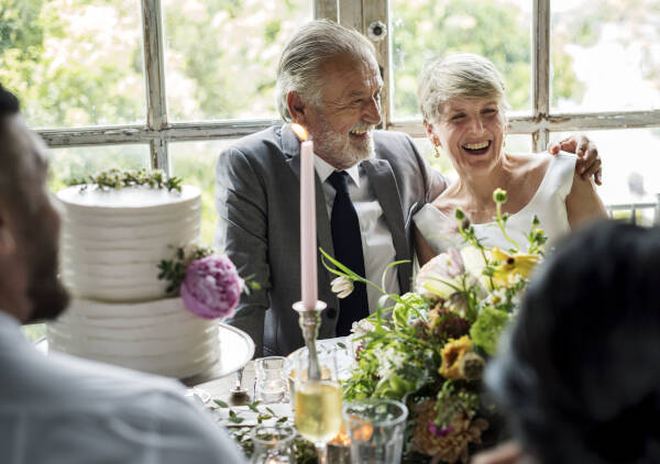 Senior bride and groom sitting together cheerfully at the wedding table