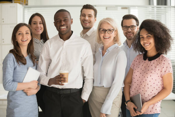 Seven smiling teachers pose for a photo, some holding notepads and one with a coffee cup