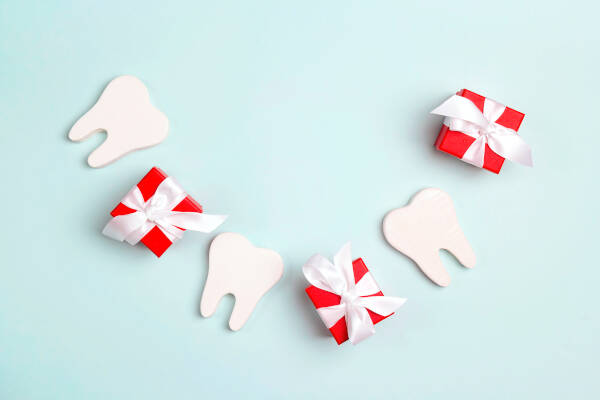 Teeth and gift boxes arranged in the form of a smile against a light blue background