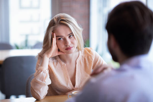 Woman appears disinterested while sitting at a table with her ex-boyfriend