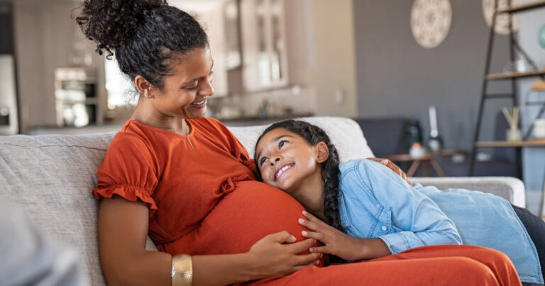 Happy daughter hugging the belly of her expecting mother.