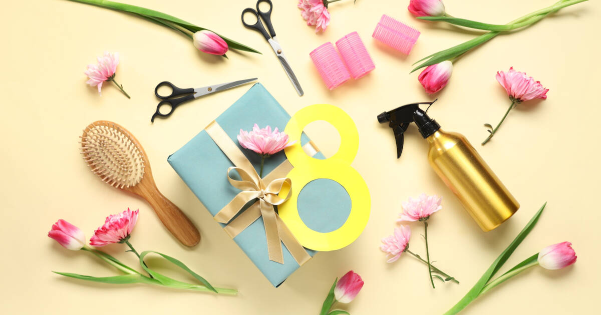 Arrangement of hairdresser's supplies, a gift box, and flowers on a colorful background.