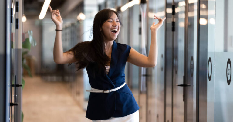 Excited businesswoman celebrates success with a victory dance in the corridor at work
