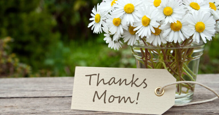 Daisies arranged on an outdoor table with a label reading 'Thanks Mom'.