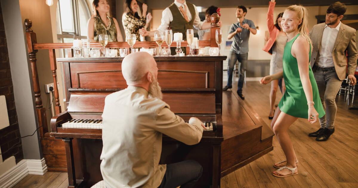 Wedding guests enjoy a dance while the uncle of the bride plays the piano.