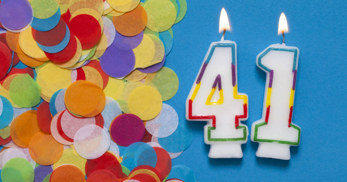 Lit '41' candles laid on a blue background surrounded by confetti.