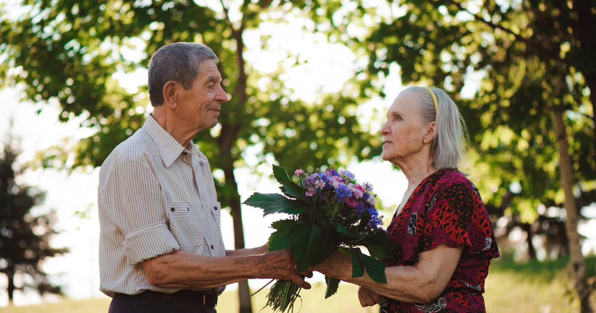 An Elderly Man Gives colorful Flowers To an elderly woman of 80 years old.
