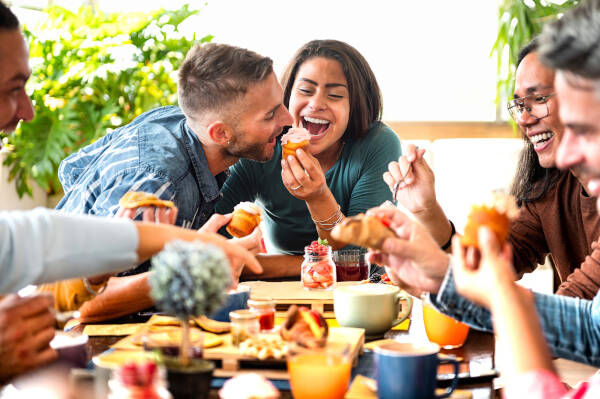 A beautiful, happy couple enjoying a cupcake with whipped cream in a cafe, as the young woman feeds her boyfriend.