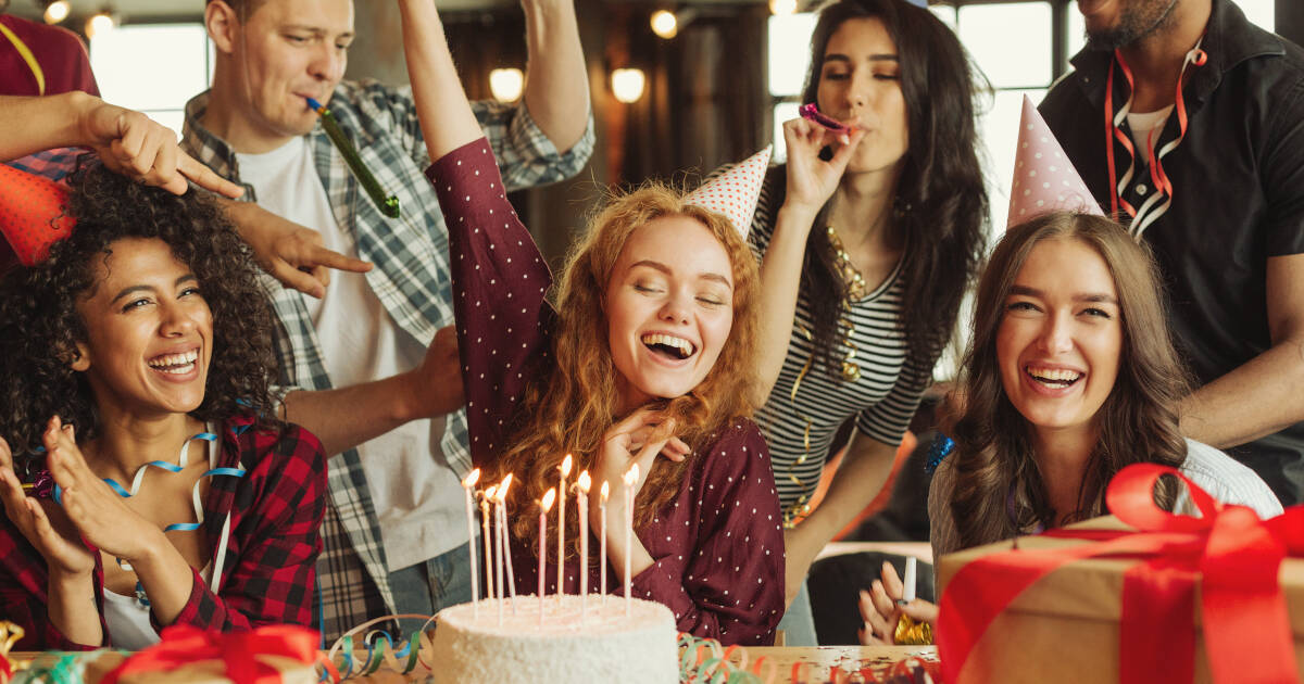 Portrait of happy friends at a birthday party with cake and presents.