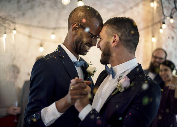 Close-up of a newlywed couple dancing at their wedding celebration. Their foreheads touching whilst holding hands.