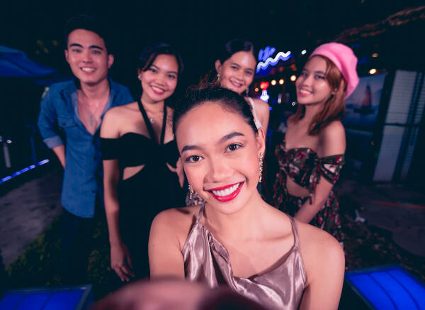 Five friends take a selfie and smile while partying at a nightclub.