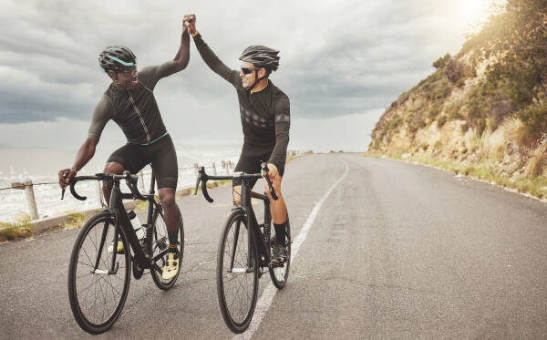 Friends on bikes high-fiving and having fun while cycling together outdoors.