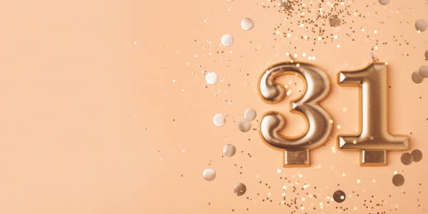 Golden '31' candles against a peach background surrounded by confetti.