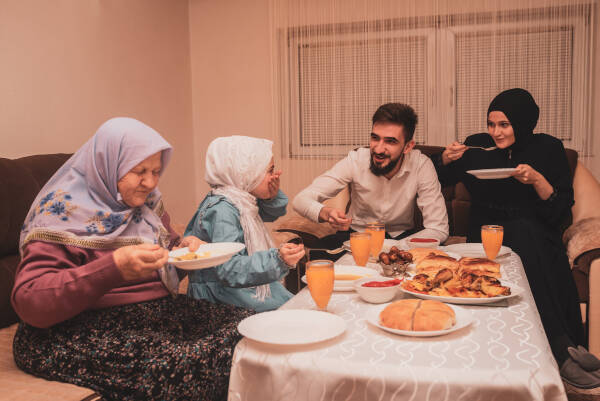 Happy family at home seated around the dinner table, enjoying a meal and conversation.