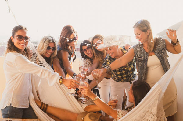 Happy group of middle-aged women toasting glasses outdoors at a birthday celebration.