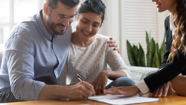 Horizontal view of a happy married couple, signing a contract at a meeting.