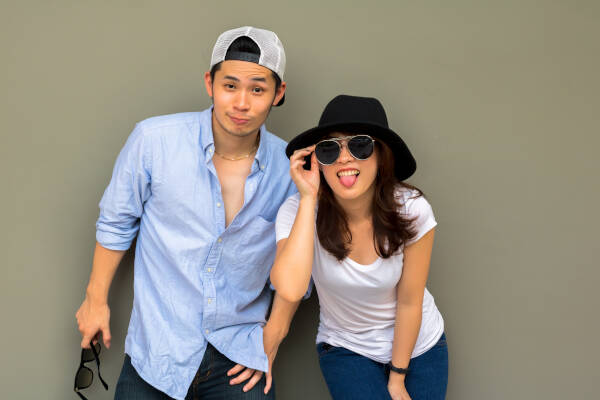 The charming male and female couple, making cheeky faces, with the female leaning forward sticking her tongue out.