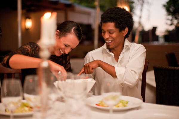 The couple enjoys dinner together, smiling as they sit outside at a restaurant.