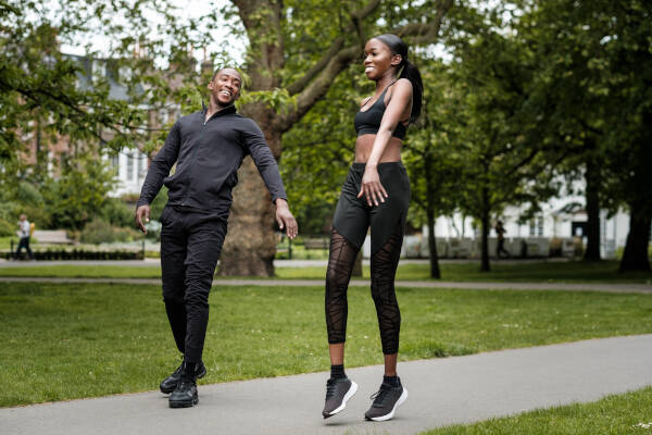 Twin brother and sister exercising in the park, both smiling.